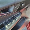 The interior door panel of the 2018 Chevrolet Cruze LT Turbo features a sleek design with lock and unlock buttons, four window control switches, and a chrome door handle. The black textured finish contrasts elegantly with the red car door frame, offering both style and functionality.