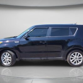 A black 2018 Kia Soul EX with four doors is displayed from the side in a well-lit studio with a neutral background. The car has tinted windows and appears clean and well-maintained.