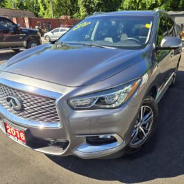 A 2016 Infiniti QX60 AWD is parked outdoors at a car dealership on a sunny day, with other vehicles and trees visible in the background.