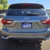 Rear view of a 2016 Infiniti QX60 AWD parked in a lot under a clear blue sky, with other cars and trees in the background. The license plate says LOADED and promotes BOSS AUTO.