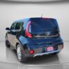 A 2018 Kia Soul EX hatchback in black is parked in a studio with a gray background, seen from the rear-left angle. A Super Clean dealer tag is displayed on the back.