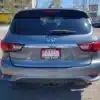 A gray 2016 Infiniti QX60 AWD SUV is parked in a lot, featuring a rear LOADED sign from Boss Auto. Trees and other vehicles are visible in the background.