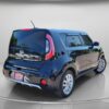 A 2018 Kia Soul EX hatchback in black is parked in a studio with a plain gray background, shown from the rear passenger side. A "SUPER CLEAN" sign is displayed on the car’s back.