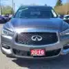 A silver 2016 Infiniti QX60 AWD, featuring chrome accents and a red 2016 license plate, is parked outdoors with a dealer tag on the windshield. Other vehicles and trees create the background for this SUV.