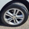 Close-up of a wheel from the 2017 Chevrolet Cruze 2LT Turbo, showcasing a silver alloy rim with the Chevrolet logo and Kumho Solus tire. A glimpse of the car body is seen against textured asphalt.