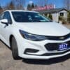 A white 2017 Chevrolet Cruze 2LT Turbo sedan sits on a gravel lot at Boss Auto Sales, adorned with a blue license plate and surrounded by trees and other cars.
