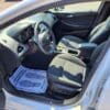 The 2017 Chevrolet Cruze 2LT Turbos interior features pristine white front seats, a standout dashboard and center console, and a Your Business is Appreciated paper mat with footprints on the driver’s side.