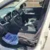 Inside the front seat of a 2015 Dodge Journey SE, the sleek black dashboard and steering wheel gleam. A paper on the passenger seat reads Thank You! We Appreciate Your Business,” highlighting the attention given to keeping this interior pristine.