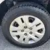 Front tire of a 2015 Dodge Journey SE on pavement, showcasing a silver alloy wheel and clear tread pattern. The word Rotation is embossed on the sidewall, with part of the vehicles white body visible above the wheel.