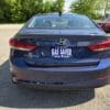 A 2018 Hyundai Elantra Limited in blue is parked in a lot, viewed from the rear, with the license plate reading GAS SAVER and BOSS AUTO; trees and other vehicles are visible in the background.