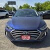 A 2018 Hyundai Elantra Limited is parked in a car lot on a sunny day, with other vehicles and a BOSS AUTO dealership sign visible in the background.