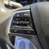 Close-up of a 2018 Hyundai Elantra Limited steering wheel with buttons for volume, call, mute, and mode selection on textured black leather, plus part of the dashboard in view.