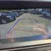 The 2018 Hyundai Elantra Limited’s rearview camera display shows yellow, red, and blue parking guidelines with parked cars on both sides and the message, Check surroundings for your safety.