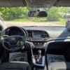 Interior view of a 2018 Hyundai Elantra Limited featuring the dashboard, steering wheel, touchscreen display, gear shift, and floor mats reading YOUR BUSINESS IS APPRECIATED! with sunlight streaming through the windshield.