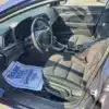 The 2018 Hyundai Elantra Limited interior includes a drivers seat, dashboard, striking steering wheel with the Hyundai logo, and a blue-and-white Thank You for Serving mat on the black-upholstered floor, all illuminated by sunlight in the parked car.