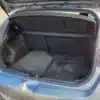 The open trunk of the 2014 Hyundai Elantra GT showcases its spacious interior, revealing two black floor mats labeled ELANTRA GT and ELANTRA. The raised trunk lid on the blue hatchback is visible as it is parked outdoors.
