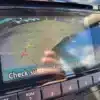 The 2014 Nissan Rogue 2.5 SVs rear-view display shows the backup camera view with parking guidelines in green, yellow, and red. A “Check surroundings for safety” message reminds drivers while dashboard controls are conveniently located below the screen.
