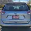 A 2014 silver Nissan Rogue 2.5 SV is parked under sunlight, displaying a Certified Boss Auto license plate, with trees and buildings partially visible in the background.