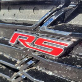 Close-up of the 2017 Chevrolet Cruze Premier Hatchback grille with a red RS badge and water droplets on the glossy black and chrome finish.