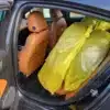 The rear door of the 2017 Chevrolet Cruze Premier Hatchback is open, showcasing tan leather seats and a large yellow plastic bag covering an object that occupies most of the backseat space.