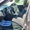 The image shows the interior of a 2016 Chevrolet Equinox LTZ AWD from the open drivers side door, featuring black and gray seats, a center console with cup holders, a steering wheel, and a floor mat with instructions on the drivers side.