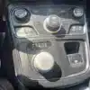 A close-up of the 2015 Chrysler 200 S AWDs central console highlights a circular gear selector with P, R, N, D, S labels, climate controls, and buttons for AC, defogging, and seat heating. The sleek black and metallic finish enhances the cars sophisticated appearance.
