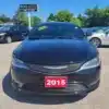 A sleek black 2015 Chrysler 200 S AWD is parked in a lot at Boss Auto, showcasing a Loaded! Low KM decal on the windshield. Other vehicles are scattered in the background, bordered by trees and a bright blue sky.