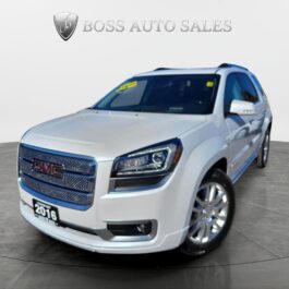 A 2016 GMC Acadia Denali AWD in white is showcased at an angle in a showroom, highlighting its front grille, headlights, and side profile with the BOSS AUTO SALES logo displayed on the wall behind it.