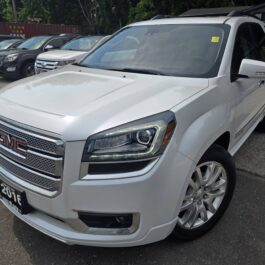 A 2016 GMC Acadia Denali AWD is parked outdoors on a lot with other vehicles, displaying a front-side view. This model features chrome accents and the GMC logo on its grille. A 2016 GMC Acadia Denali AWD is parked outdoors on a lot with other vehicles, displaying a front-side view. This model features chrome accents and the GMC logo on its grille.