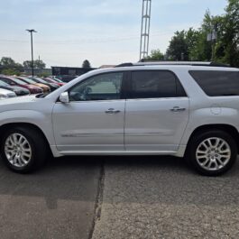 A 2016 GMC Acadia Denali AWD is parked in a lot with several other cars in the background, under a partly cloudy sky with trees and utility poles nearby. A 2016 GMC Acadia Denali AWD is parked in a lot with several other cars in the background, under a partly cloudy sky with trees and utility poles nearby.