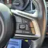 A close-up of the 2017 Subaru Impreza Premium HB steering wheel shows control buttons including RES/+ for resume/accelerate, SET/- for set/slow, a speedometer icon, and CANCEL. Dashboard dials in the background enhance its design.