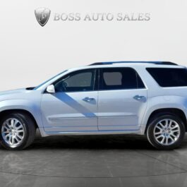 A 2016 GMC Acadia Denali AWD is parked in a showroom, with the Boss Auto Sales logo and text visible on the white wall behind the vehicle.
