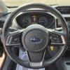 A close-up of the 2017 Subaru Impreza Premium HB steering wheel with mounted controls, dashboard gauges, and infotainment screen; climate control dials sit below the screen in this modern interior.