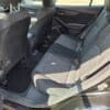 The image shows the backseat area of a 2017 Subaru Impreza Premium HB with black cloth seats, an open door, and sunlight illuminating the spacious bench seat and ample legroom.