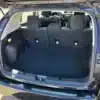 The open trunk of a 2017 Subaru Impreza Premium HB shows a sunlit, spacious, and pristine cargo area. With rear seats upright, the interior stays clean, while the dashboard and front seats are visible through the rear window.