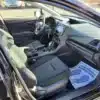 The image depicts the interior of a 2017 Subaru Impreza Premium HB from the passenger side, highlighting gray fabric seats, a steering wheel, and a digital dashboard. A paper mat with shoe prints and YOUR BUSINESS IS APPRECIATED! is on the floor of this sleek car.