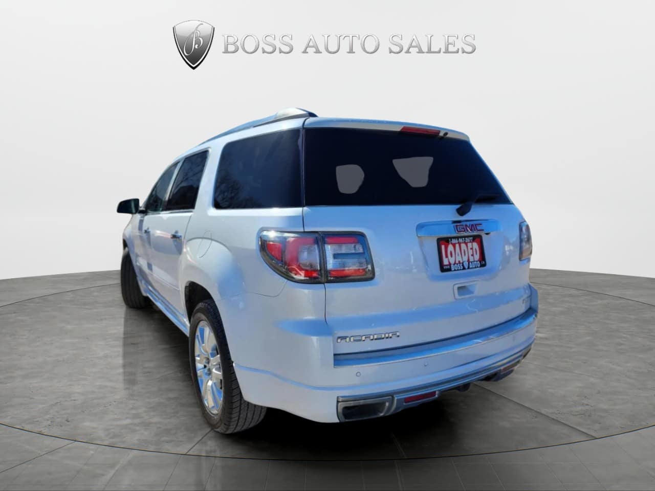 A 2016 GMC Acadia Denali AWD in white is parked indoors facing away from the camera. The rear license plate reads "LOADED," with the Boss Auto Sales logo visible at the top of the image.