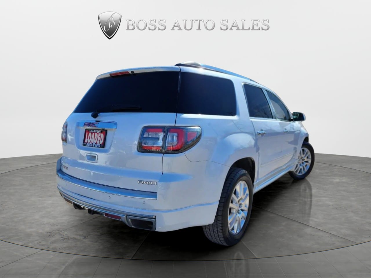 A silver 2016 GMC Acadia Denali AWD is displayed from the rear driver’s side on a circular platform with “BOSS AUTO SALES” above, a “LOADED” dealer plate, and tinted windows.
