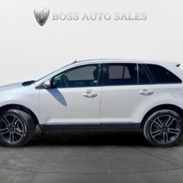 A 2013 Ford Edge SEL V6 with black trim and alloy wheels is parked indoors on a gray floor, shown from the side, with the Boss Auto Sales sign visible in the background.