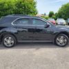 A 2017 Chevrolet Equinox 2LT AWD in black is parked in a lot on a sunny day, with other vehicles and green trees visible in the background.