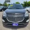 A 2017 Chevrolet Equinox 2LT AWD is parked in a lot, displaying a Loaded Special sign on its windshield and a 2017 Boss Auto front license plate. A dealership sign and trees create a scenic backdrop for this black SUV.
