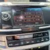 The 2015 Honda Accord Touring V6 infotainment system displays radio frequencies in MHz, with climate control buttons below for temperature, fan speed, and air circulation settings. Sunlight reflects elegantly on the surfaces of this model.