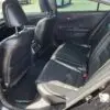 Sunlight highlights the smooth texture of the black leather seats and spotless floor in the slightly ajar backseat of the 2015 Honda Accord Touring V6, offering a glimpse of elegance and comfort.