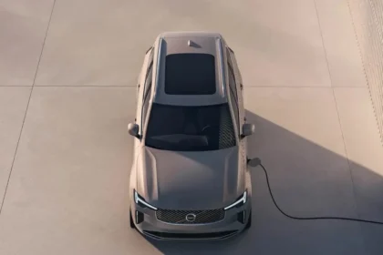 A sleek, silver Volvo electric SUV is parked and connected to a charging station on a light-colored concrete surface. Sunlight casts shadows as the image captures the vehicles roof from a high angle, reflecting Volvos commitment to EVs-by-2030. A sleek, silver Volvo electric SUV is parked and connected to a charging station on a light-colored concrete surface. Sunlight casts shadows as the image captures the vehicles roof from a high angle, reflecting Volvos commitment to EVs-by-2030.