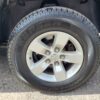Close-up of a Kapsen car tire on a silver alloy wheel with five lug nuts, enhancing the rugged design of a 2017 Dodge Ram 1500 ST 4X4, against a rough concrete background.