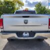 A silver 2017 Dodge Ram 1500 ST 4X4 with a Boss Auto dealership plate is parked in a lot. Trees and other vehicles are visible under a partly cloudy sky.
