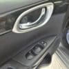 Close-up of a 2018 Nissan Sentra SV interior door panel with a silver handle, black trim, and power window controls. The open door reveals a mat on the ground partially reading BUSINESS APPRECIATED!.