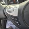 The steering wheel of the 2018 Nissan Sentra SV features audio control buttons, an Enter button encircled by a directional pad, plus additional buttons for volume and phone call management, with dashboard gauges visible in the background.
