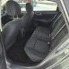 Interior of a 2018 Nissan Sentra SV highlighting the backseat with black fabric upholstery and visible seatbelts. The carpeted floor enhances the sleek design, while parts of the front seats and dashboard are in view against a snowy landscape outside.