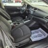 The interior of a 2018 Nissan Sentra SV features front seats, a dashboard, and a steering wheel. A passenger-side floor mat playfully displays feet with Your Shoes Are Appreciated, set against an outdoor snowy backdrop.